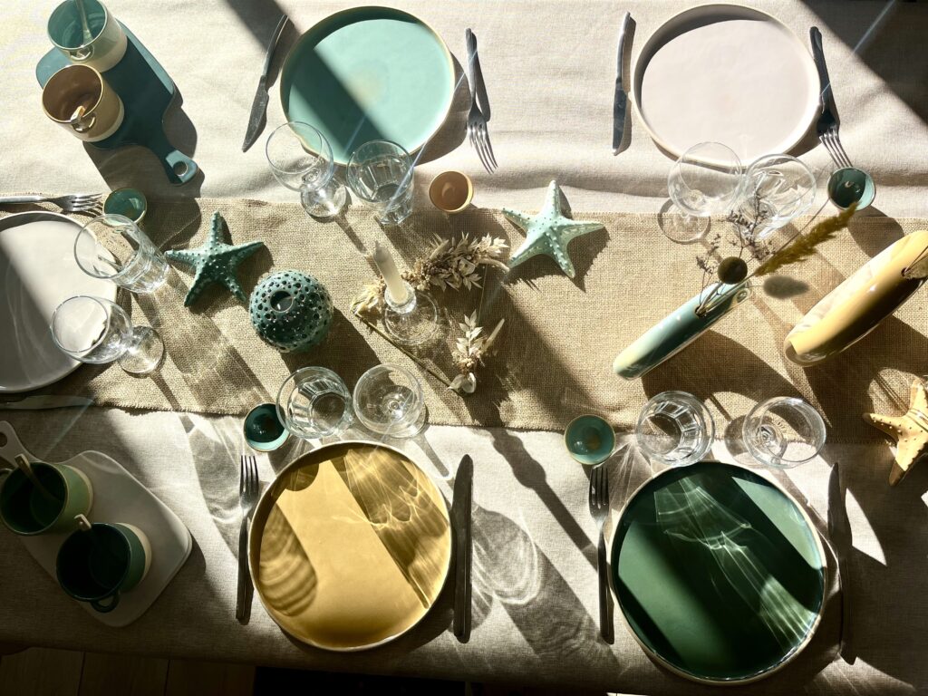 Table de présentation avec assiettes, vases, photophores, étoiles et contenant pour l'apéro en céramique fait main.